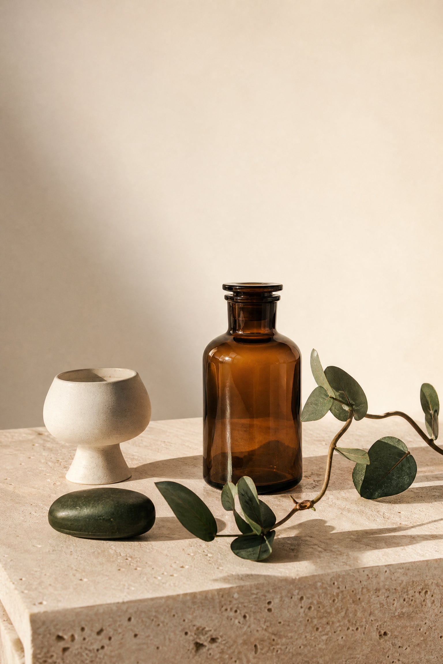A calm Lifestyle Outlet still life with warm stone, ceramic and greenery